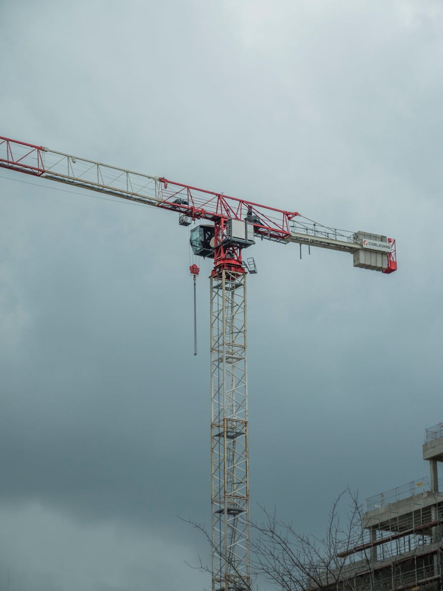 A towering construction crane amid the skyline of Wrocław, Poland, under a cloudy sky.